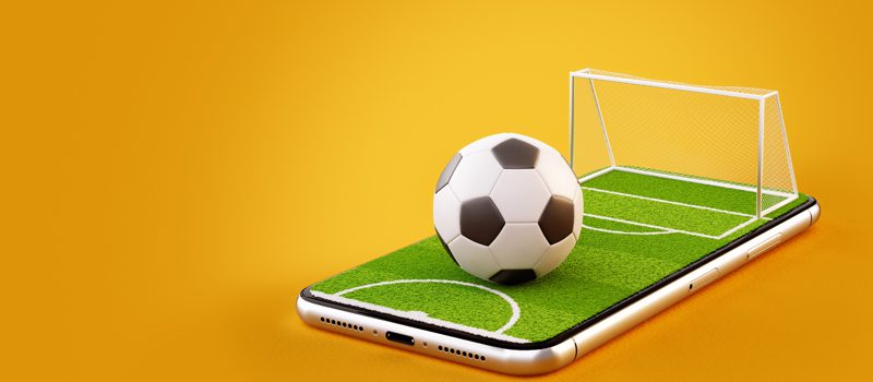 Campo e bola de futebol em cima de tela de celular Campo e bola de futebol em cima de tela de celular