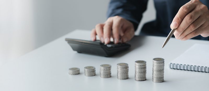 Homem com calculadora e pilha de moedas Homem com calculadora e pilha de moedas