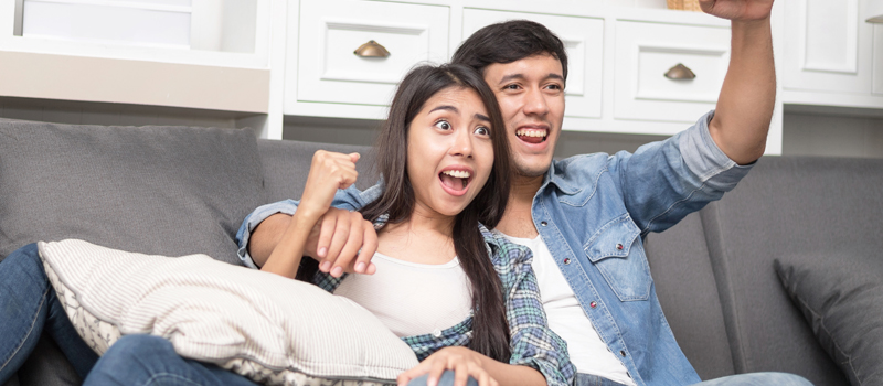 Homem e mulher assistindo tv e torcendo juntos