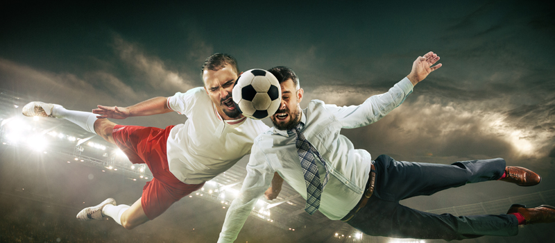 Jogador de futebol disputando bola com homem de terno