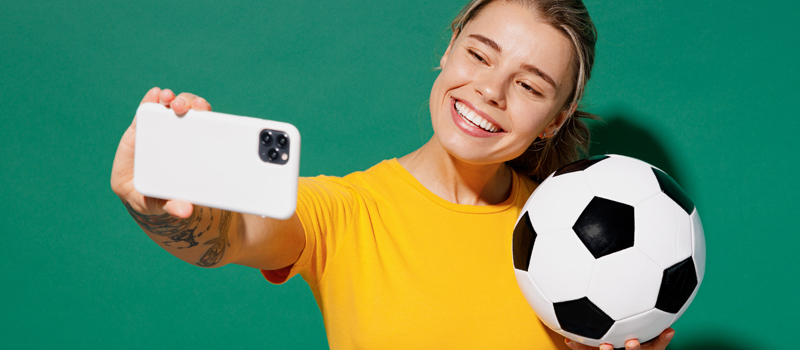 Menina posando para foto com bola de futebol na mão