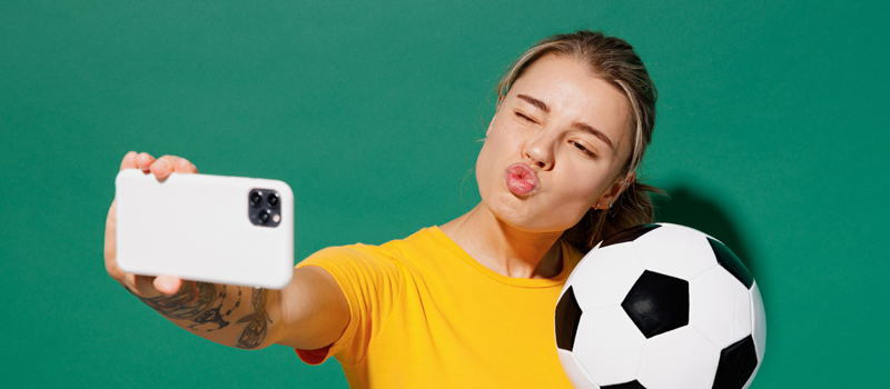 Mulher posando para foto junto a bola de futebol